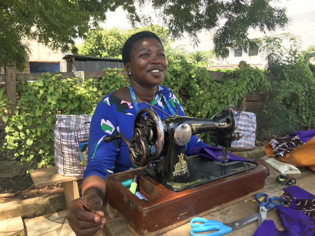 A seamstress sewing outside in Accra Ghana with her manual sewing machine