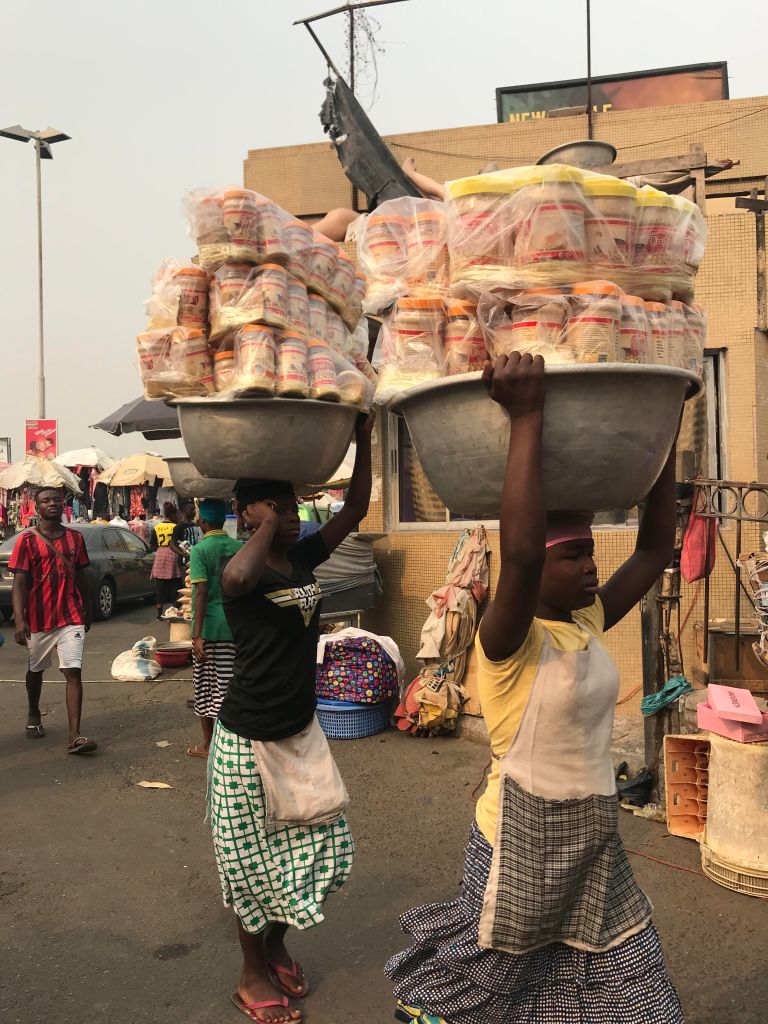 Kayayo girls (carrier girls) carrying heavy loads at Makola Market