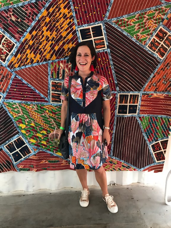 Blogger Lauren Simpson stands in front of Ghanaian artist Tei Huagie's quilts made from African wax fabrics