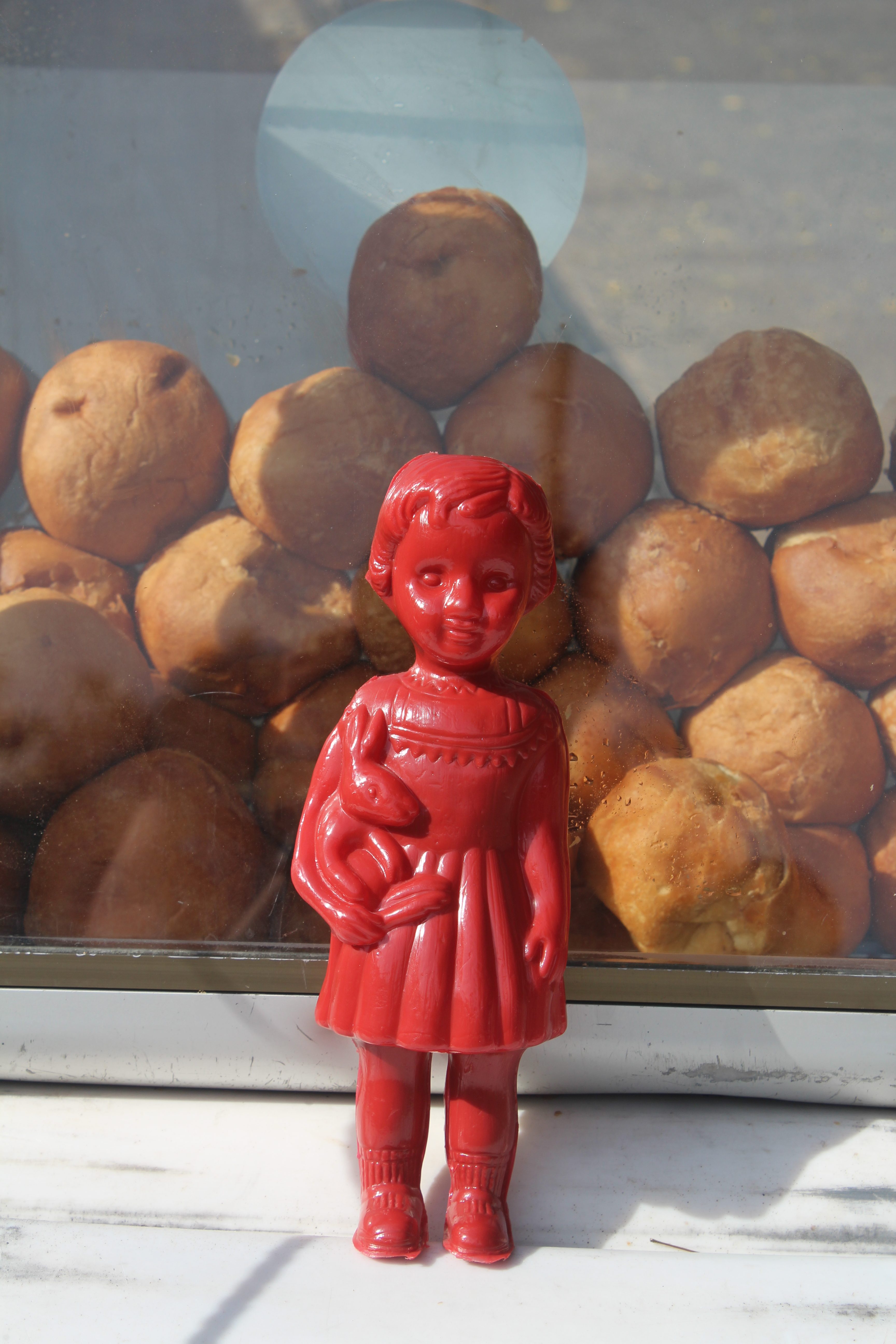 A Red Clonette doll stands in front of a bike selling bofrot in Accra Ghana