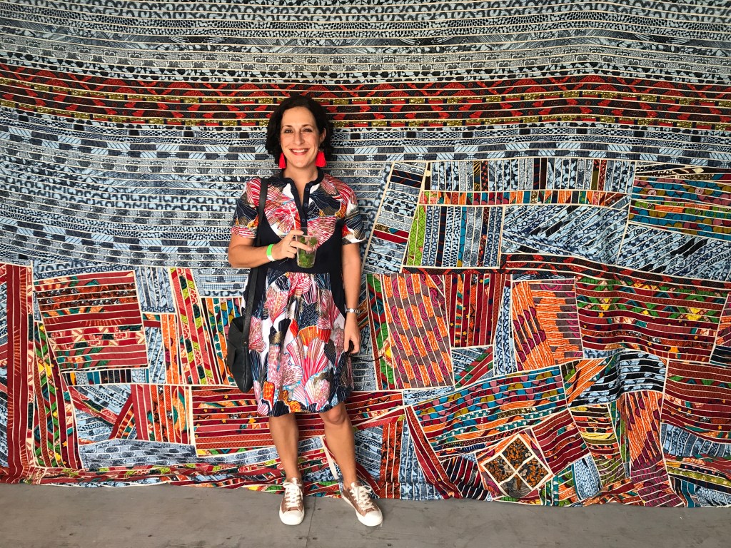 BloBlogger Lauren Simpson stands in front of Ghanaian artist Tei Huagie's quilts made from African wax fabrics