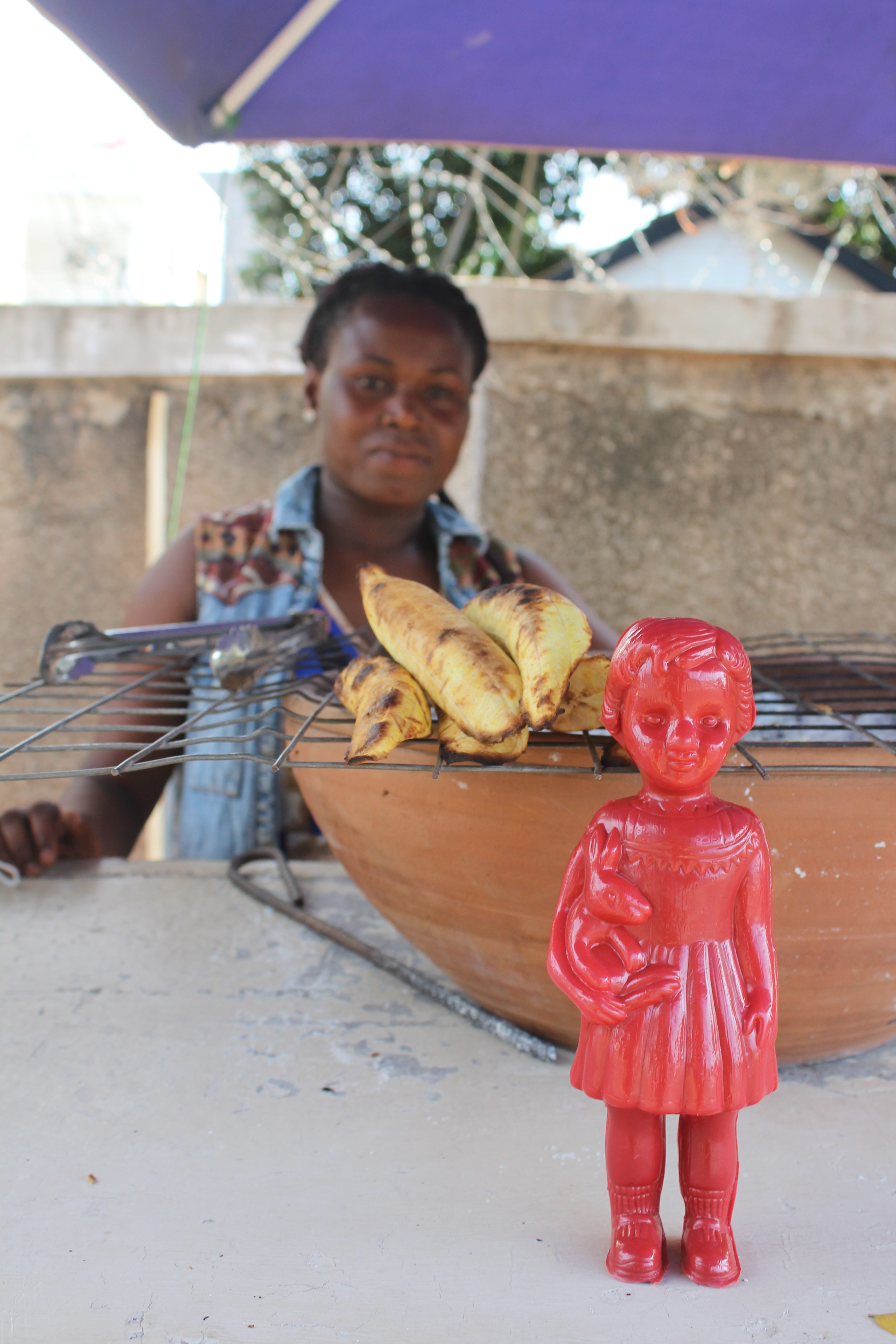 Red Clonette doll in Accra Ghana with a lady selling plantain